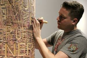 Tim Laidler carves the surface of a tribute pole being created by veterans. Photo: YOLANDE COLE 